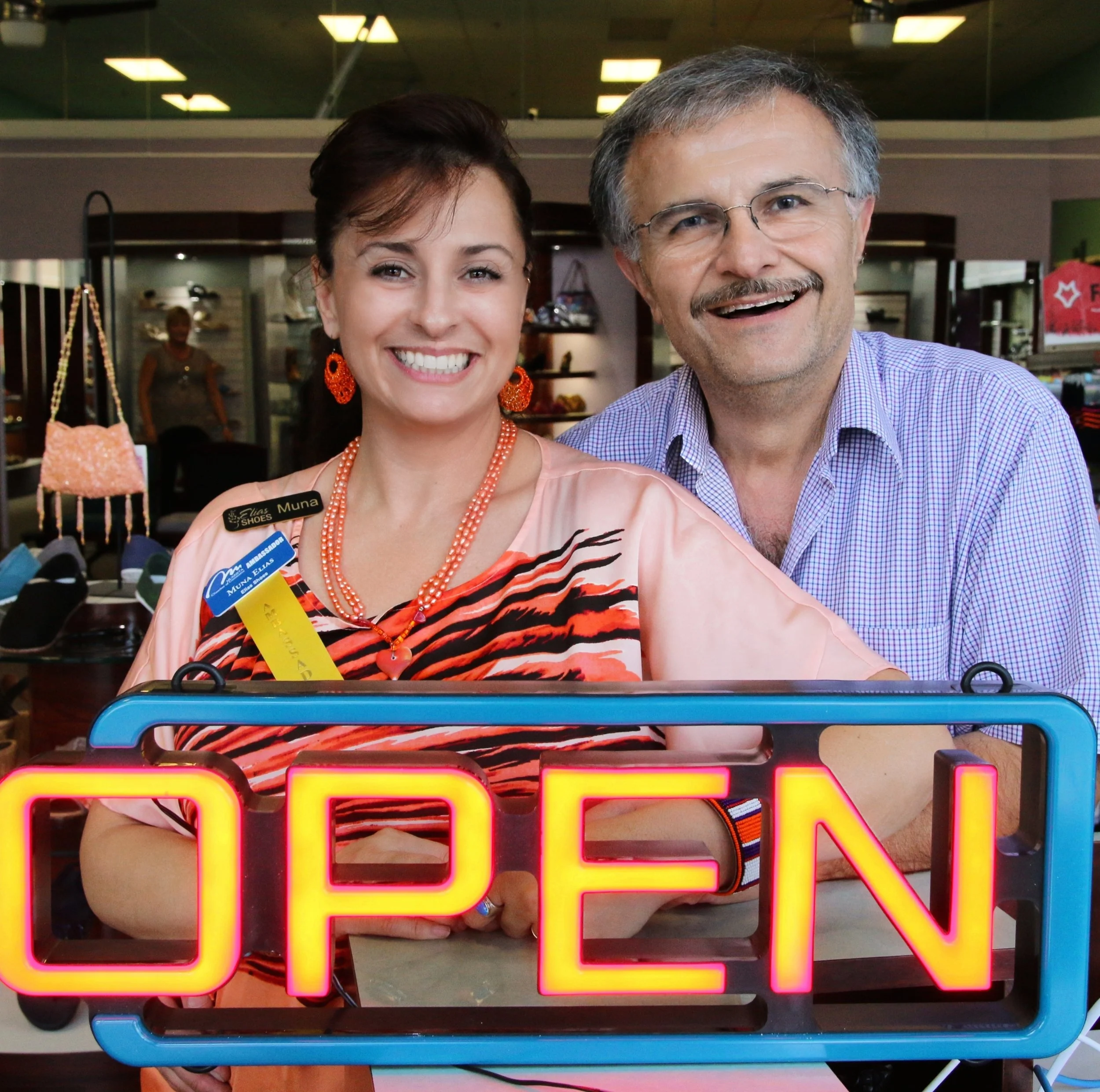 Muna Elias and family at the Elias Shoes storefront with OPEN sign